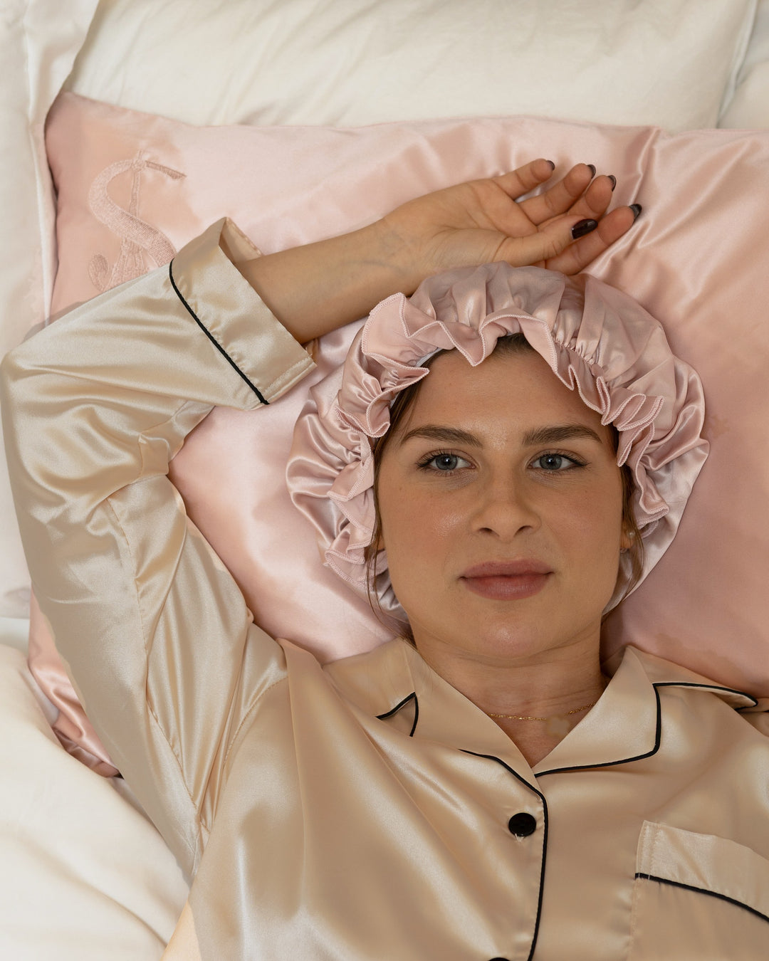 Une femme coiffée du bonnet Comfort or rose, sur la taie en soie Siluxe or rose