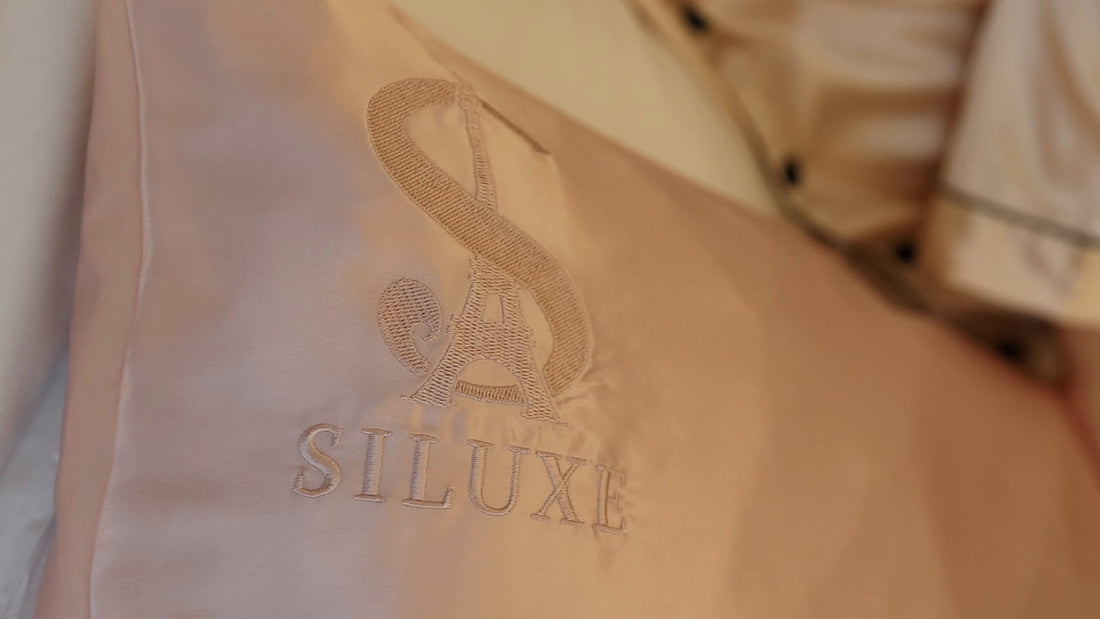 A close-up of a Rose gold silk pillowcase with its embroidered S monogram and SILUXE wordmark