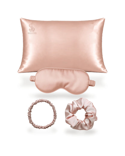 Siluxe GiftBox in Rose gold, the four pieces shown without the box: a silk pillowcase (Standard 50 × 70 cm shown), a silk eye mask, a scrunchie M and a scrunchie L, all in Rose gold