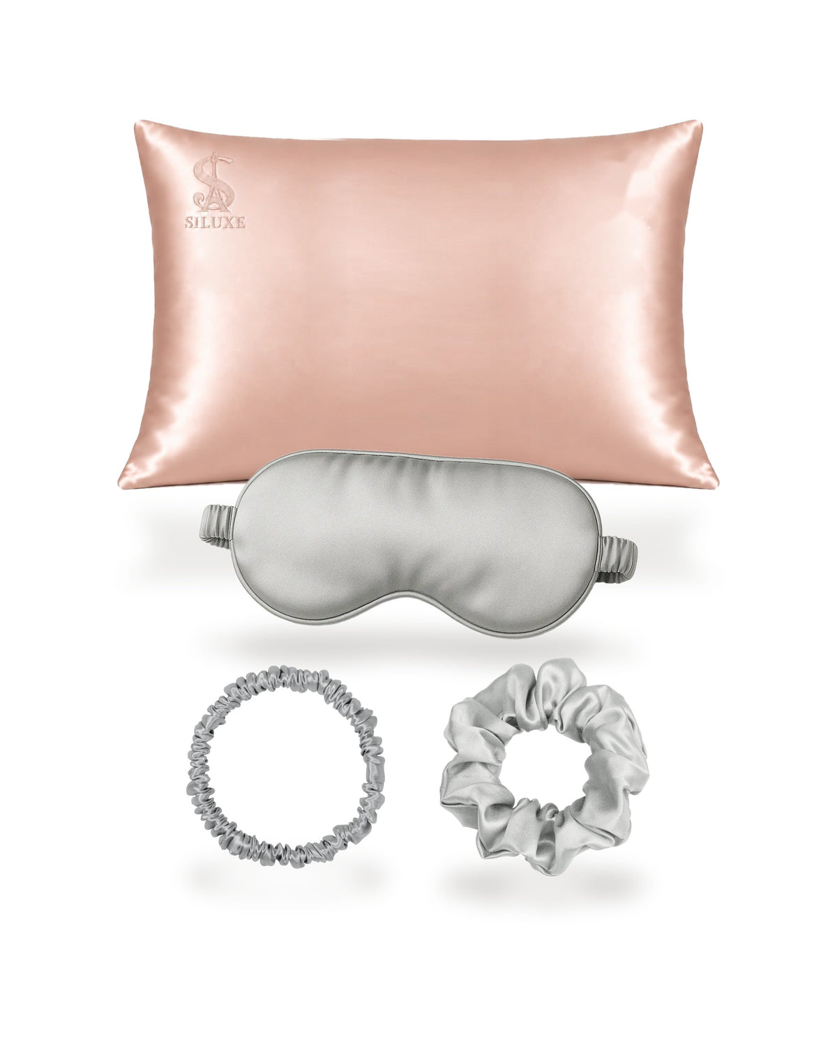 Siluxe GiftBox in Silver, the four pieces shown without the box: a Rose gold silk pillowcase (Standard 50 × 70 cm shown), with a Silver silk eye mask, scrunchie M and scrunchie L